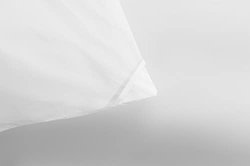 Close-up of a white pillowcase corner against a gray background